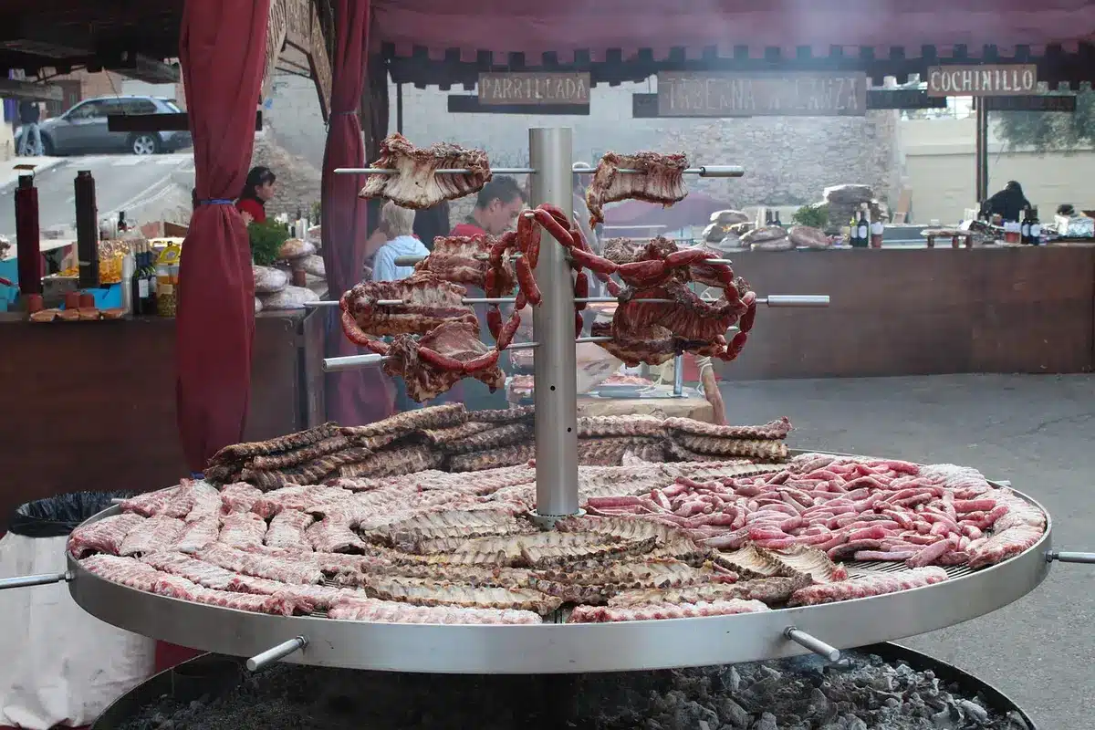 Open grillroom with charcoal fire, skylight and anonymous hands tending skewers
