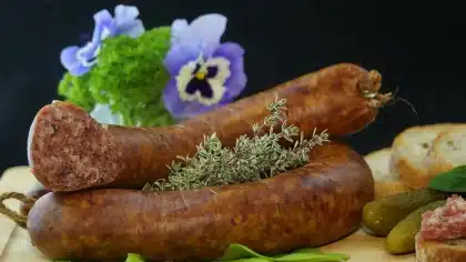 Steaming bowl of hearty stew with root vegetables and fresh herbs on a wooden table