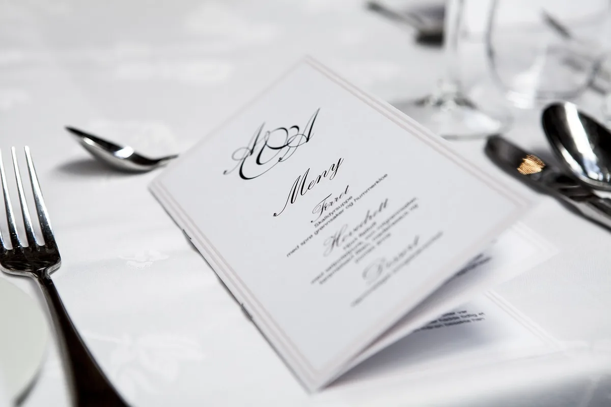 Elegant fine dining room with white tablecloths, candlelit tables, and polished service in an upscale restaurant setting