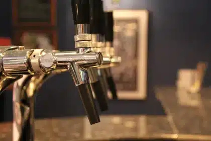 Two bourbon bottles displayed on a bar counter with ice and a glass