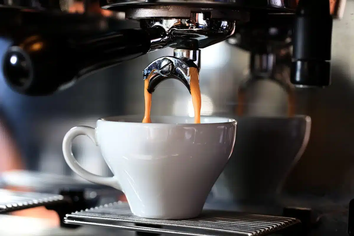 Spoon of espresso powder and whole coffee beans beside chocolate