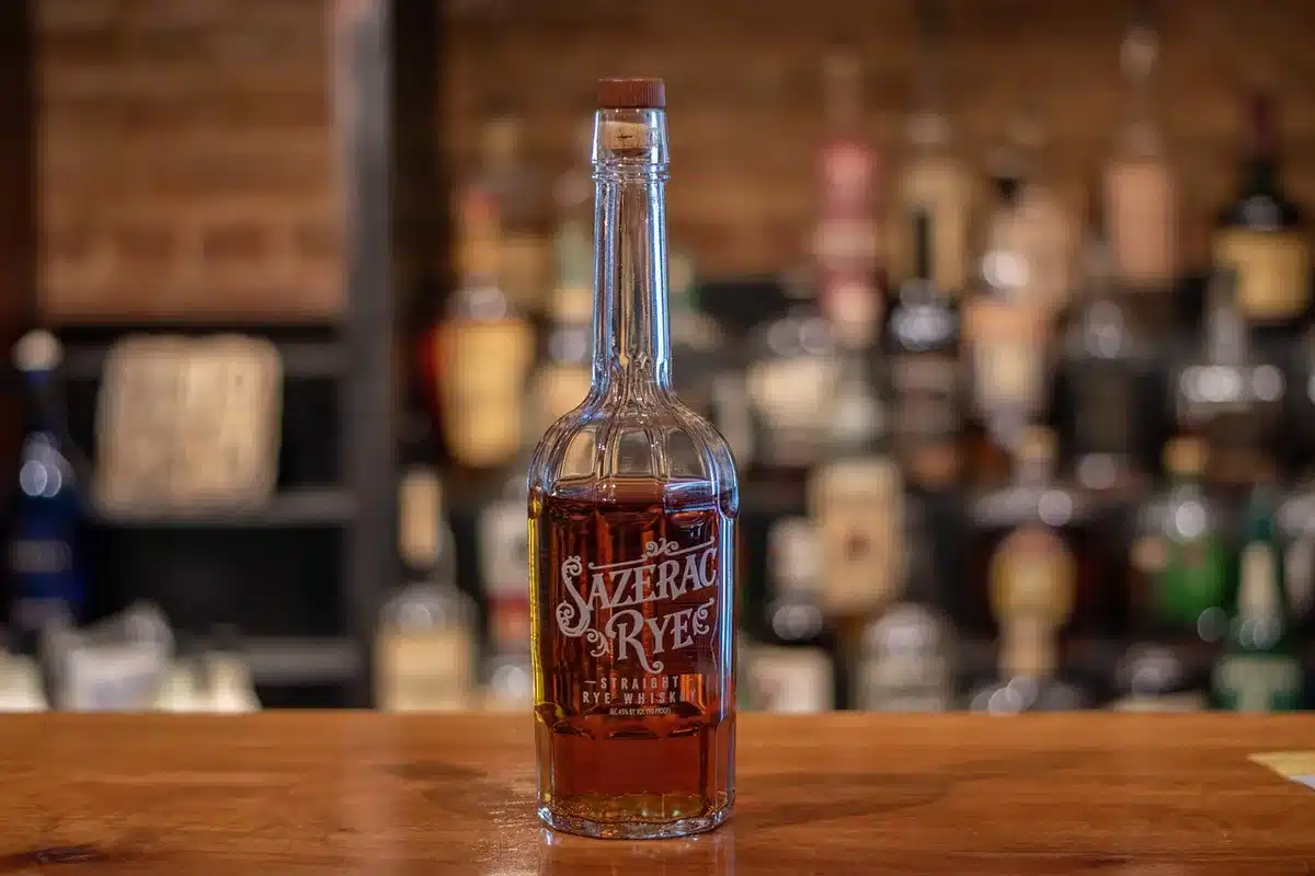 A bottle of rye whisky next to mixed cocktails and highball drinks