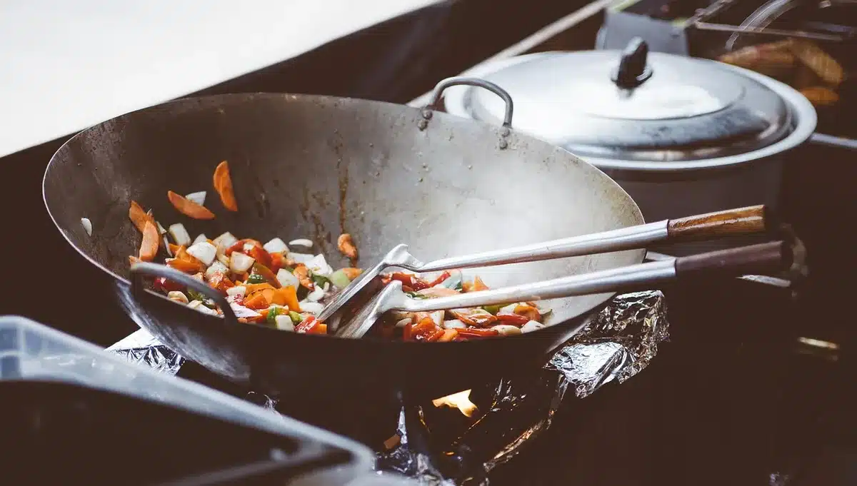 Sliced chicken and frozen vegetables cooking together in a wok with sauce