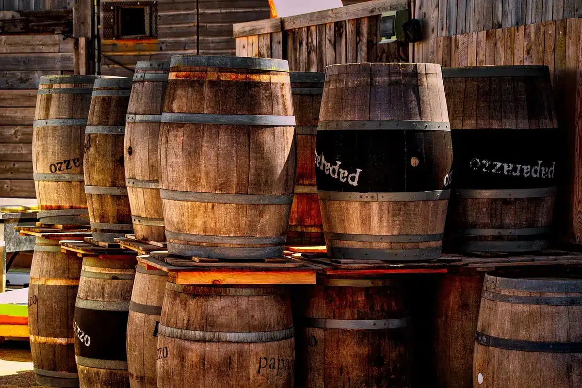 Rows of charred oak bourbon barrels aging in a dim warehouse