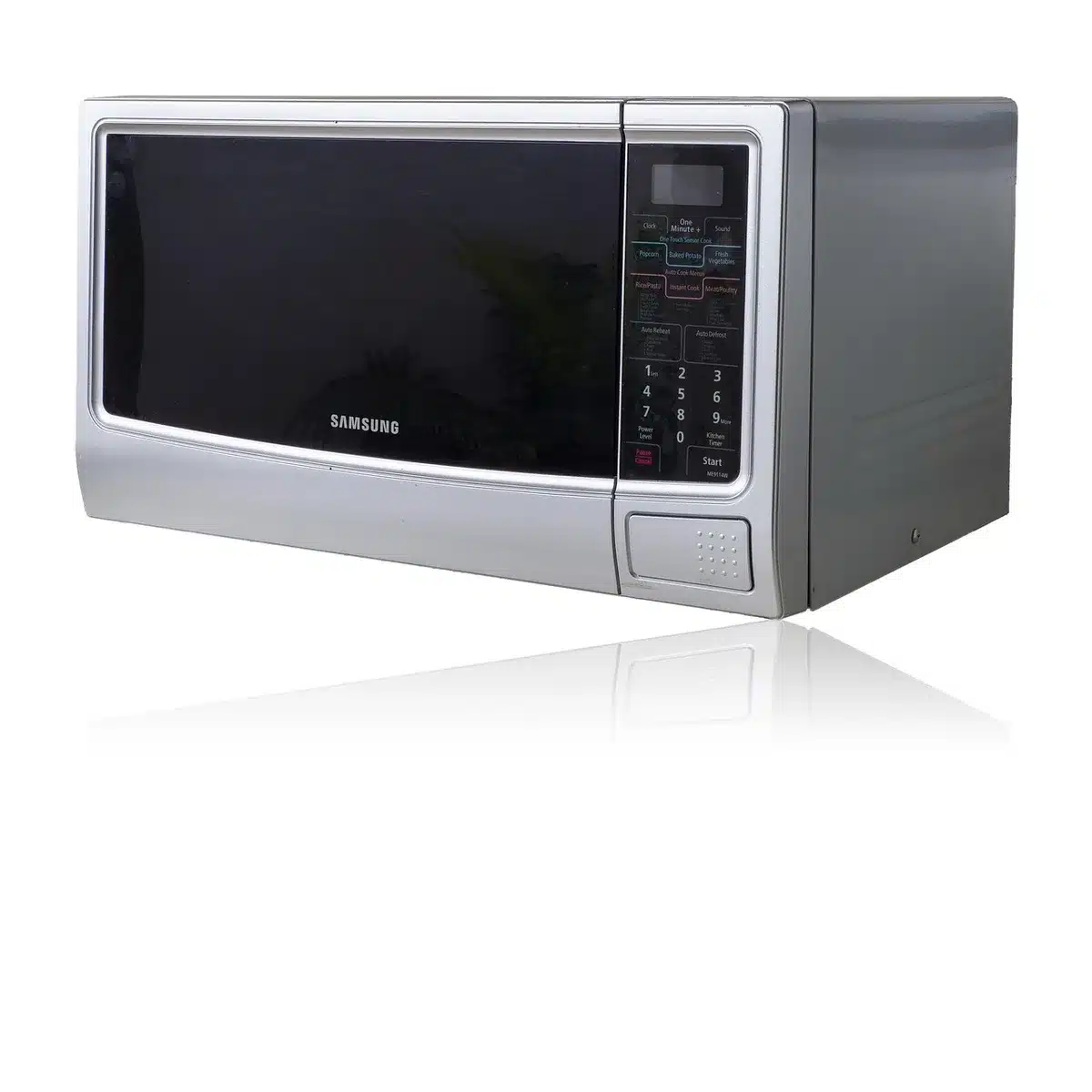 Chicken pieces arranged on a microwave-safe plate with defrost settings displayed on the microwave.