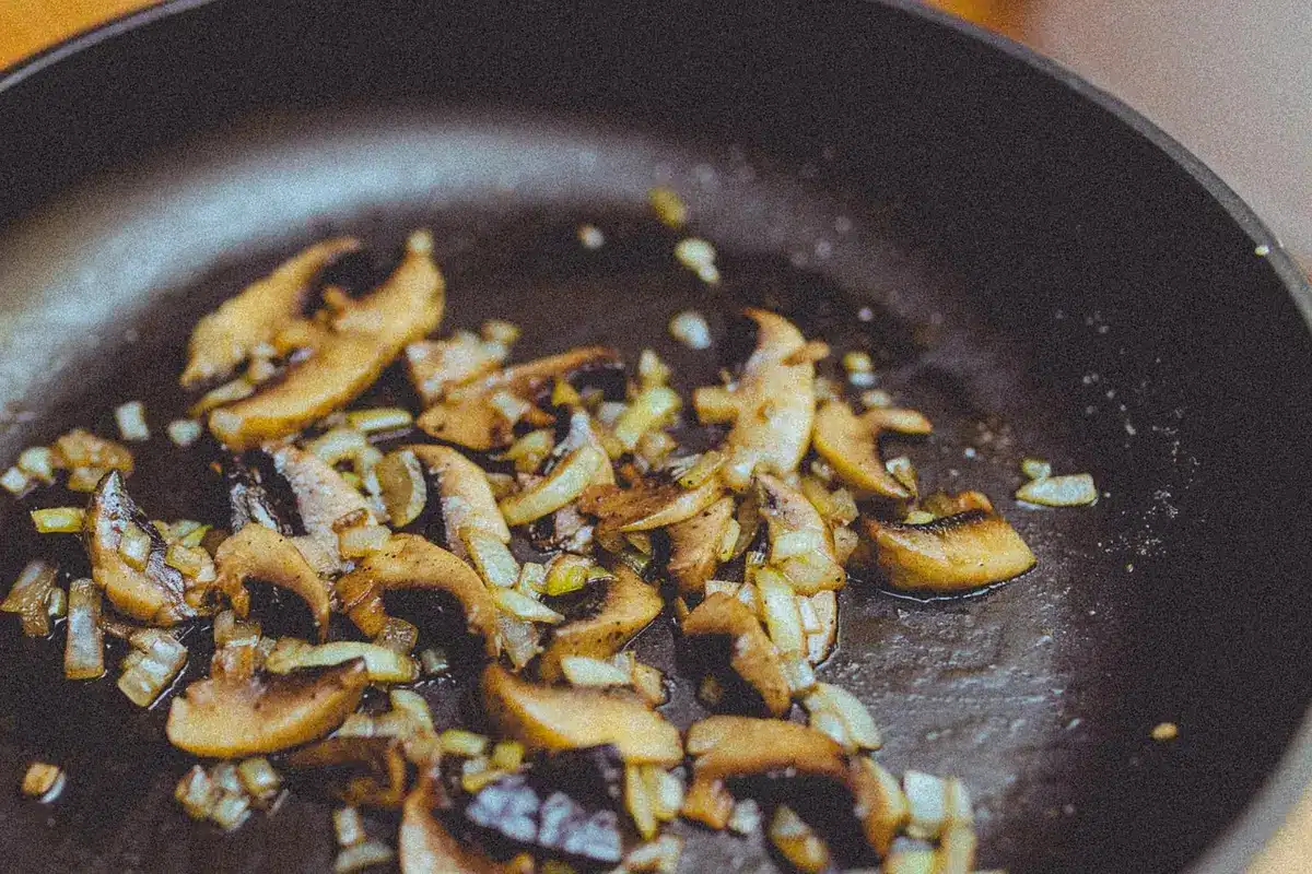 Skillet with orzo, spinach and crumbled feta being stirred