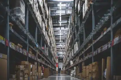 Anonymous hands passing a plain unlabeled bottle in a warehouse-style liquor aisle