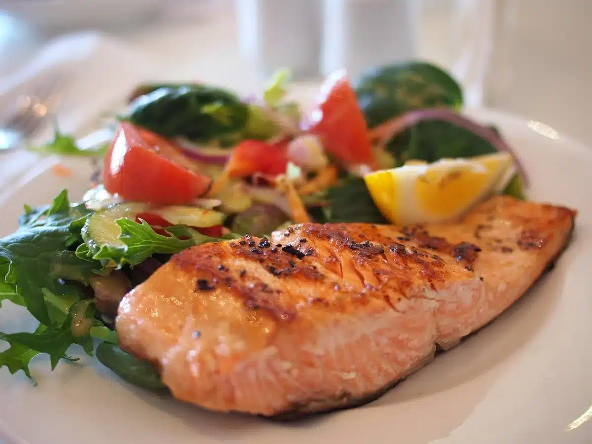 Poached salmon served on a plate with fresh green salad and crusty bread