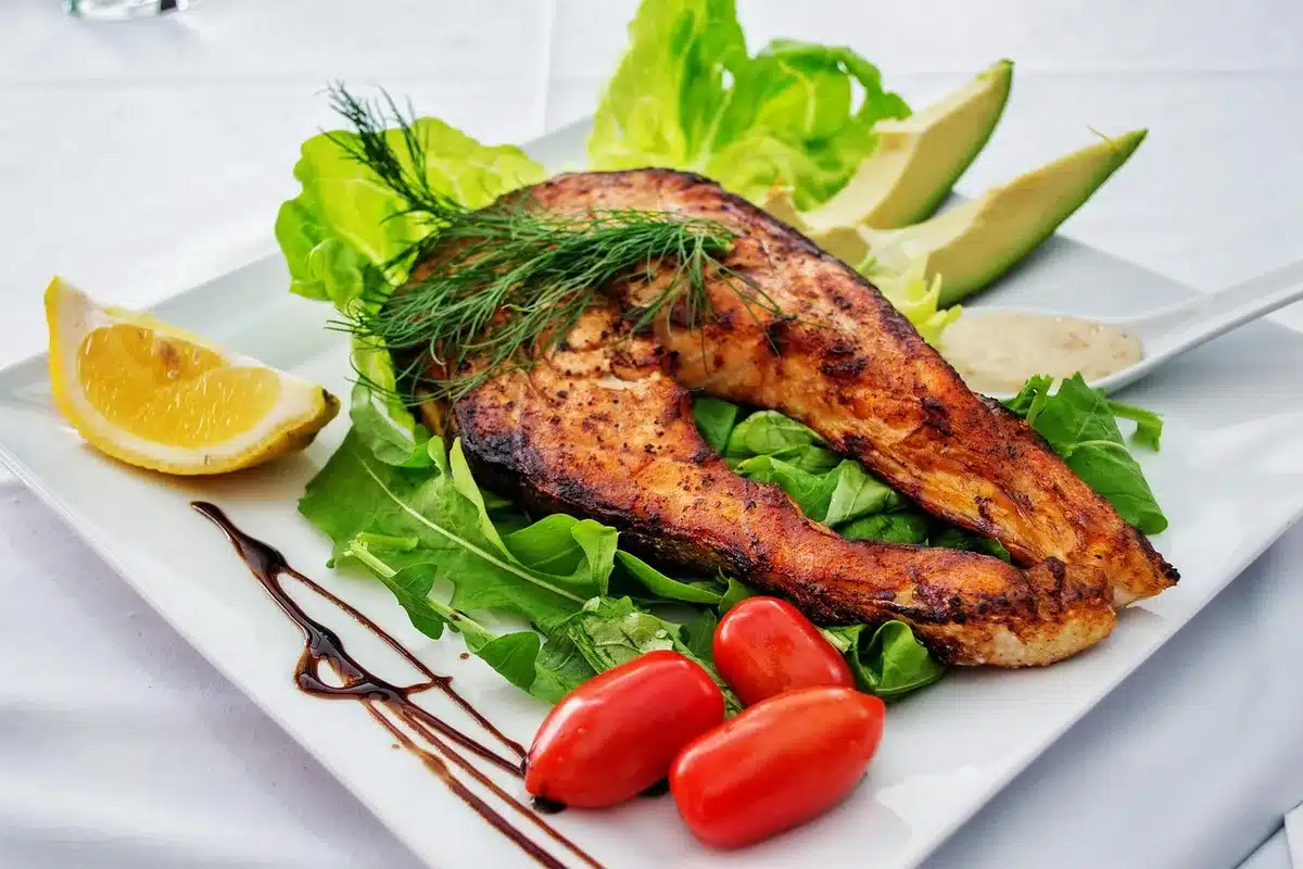 Sheet-pan salmon with roasted seasonal vegetables and lemon wedge on a baking tray