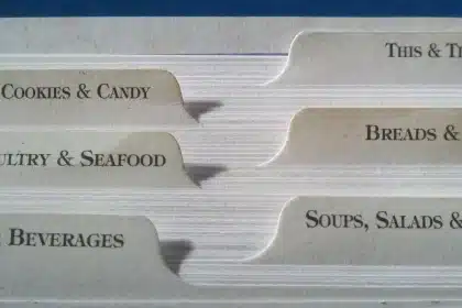 Steam rising from a bowl of clear seafood soup beside crusty bread and a ladle