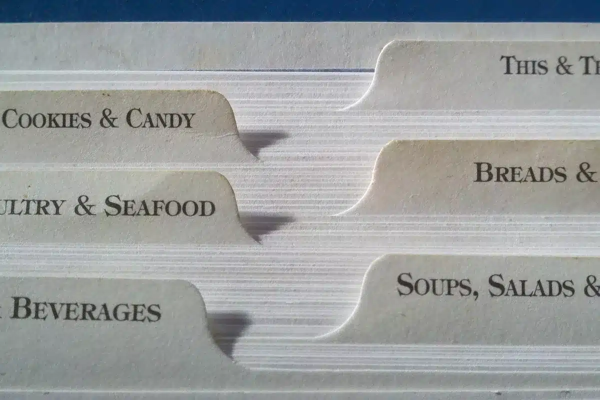 Steam rising from a bowl of clear seafood soup beside crusty bread and a ladle