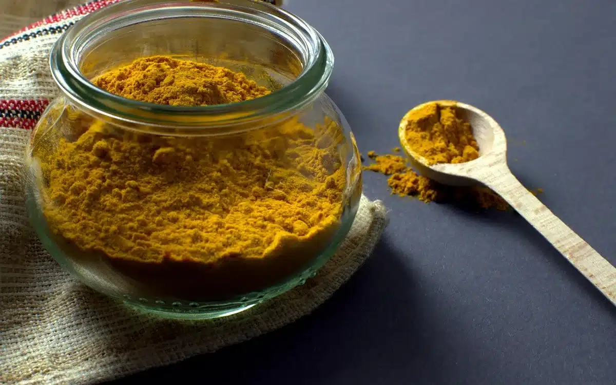 Wooden spoon lifting glossy dulce de leche from a jar beside crepes and sea salt