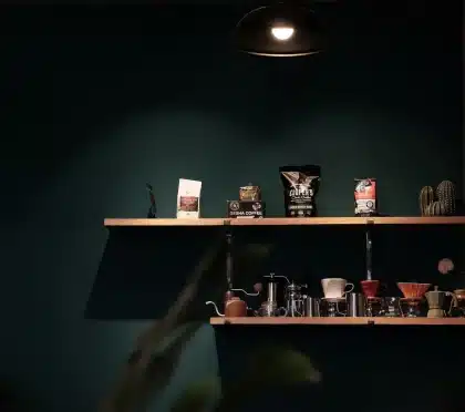 Faded vintage coffee cans on an antique shop shelf with a hand reaching for one