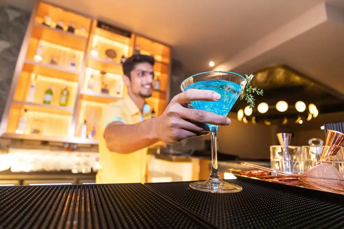 Busy restaurant bar with anonymous bartenders and a tray of mixed drinks