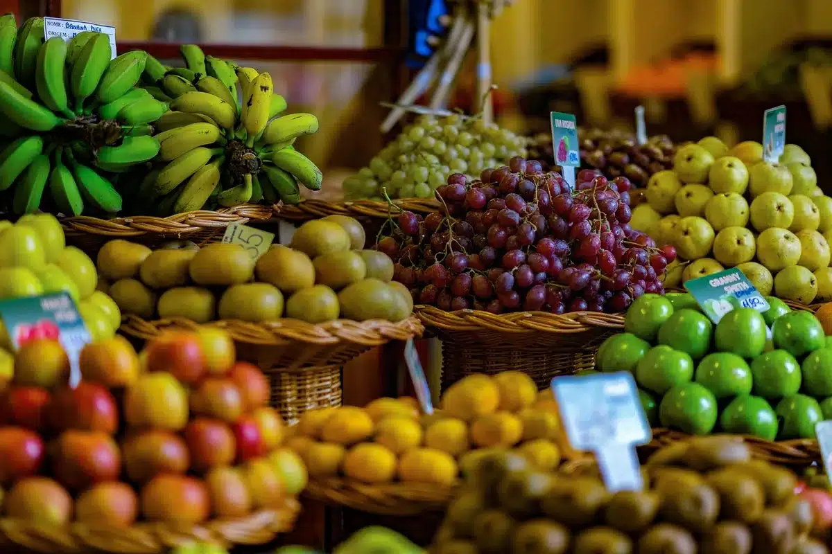 Shoppers at a market selecting plantains and root vegetables
