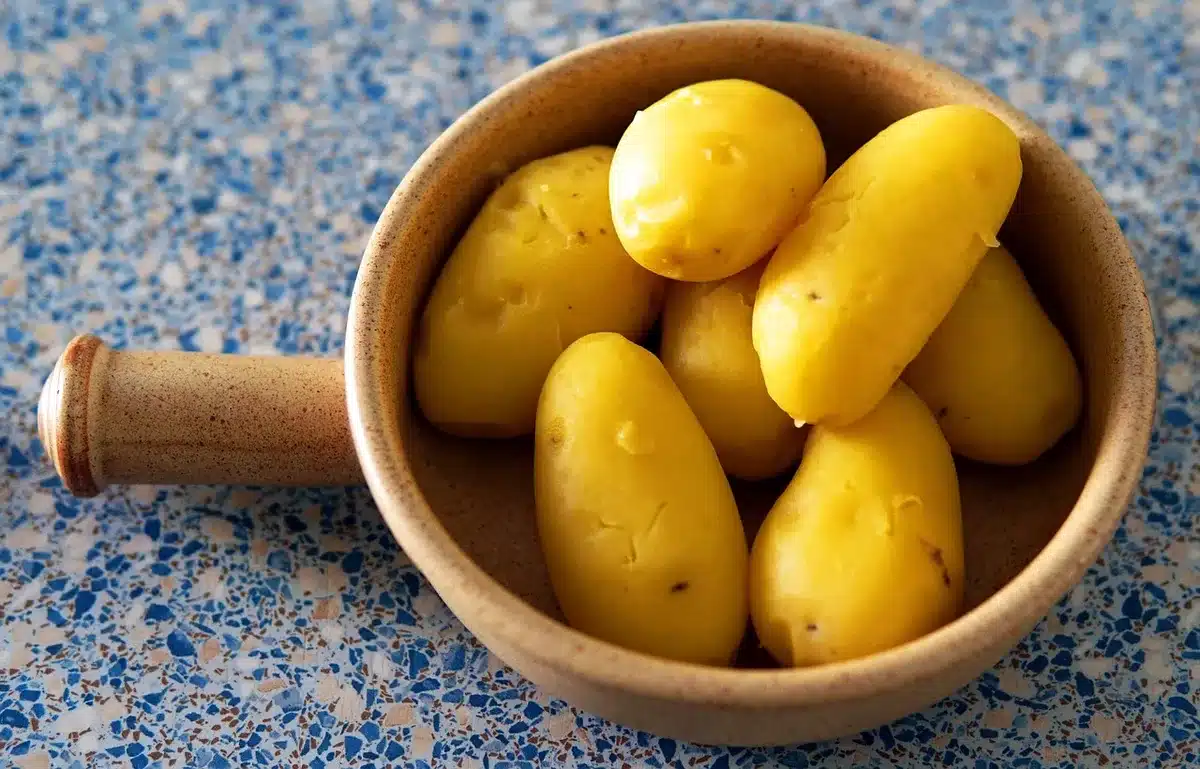 Small potatoes draining in a colander and drying on a kitchen towel