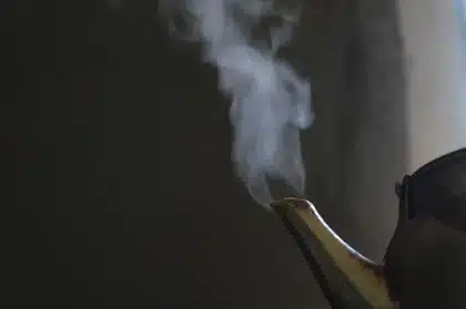 Hands working masa at a molino with dried corn nearby on a prep table