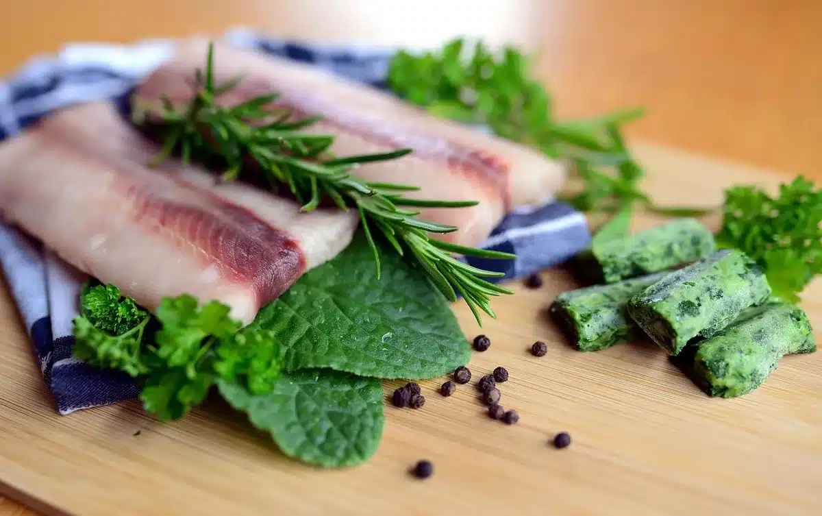 Hands using a fillet knife to slice along a fish backbone on a board
