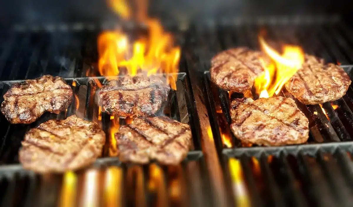 Formed frozen rib-shaped patty on a griddle under a press
