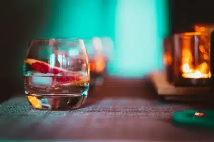 Glass of pink gin with ice, strawberries and tonic on a bar counter