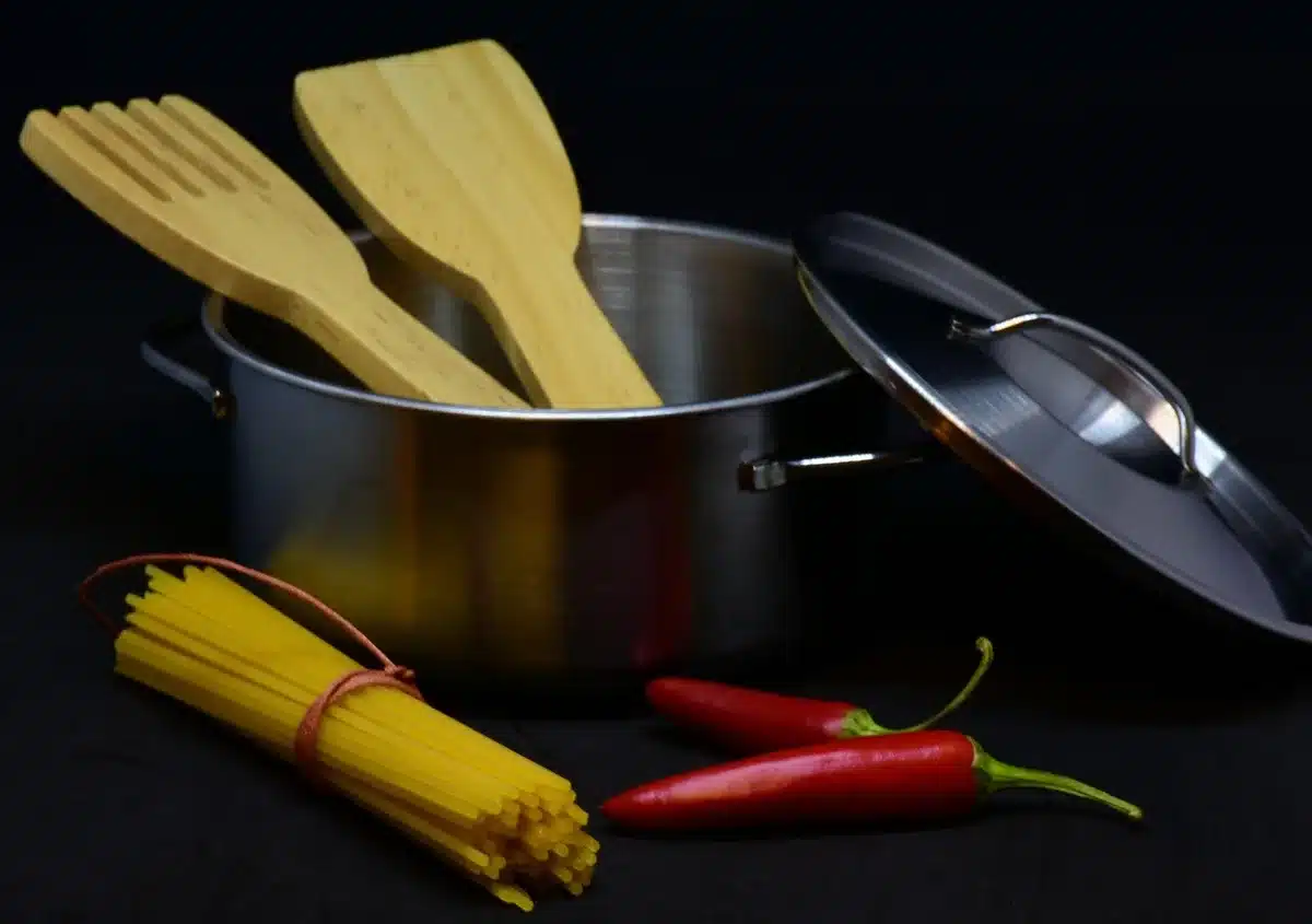 Pot of pasta boiling on the stove with salt and a wooden spoon